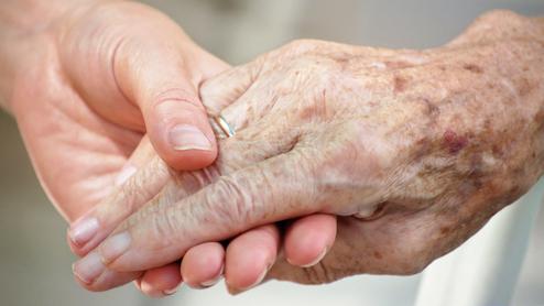 Nahaufnahme zweier Hände, eine ältere und eine jüngere, die sich liebevoll halten.